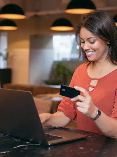 Mulher segurando cartão na frente de um notebook